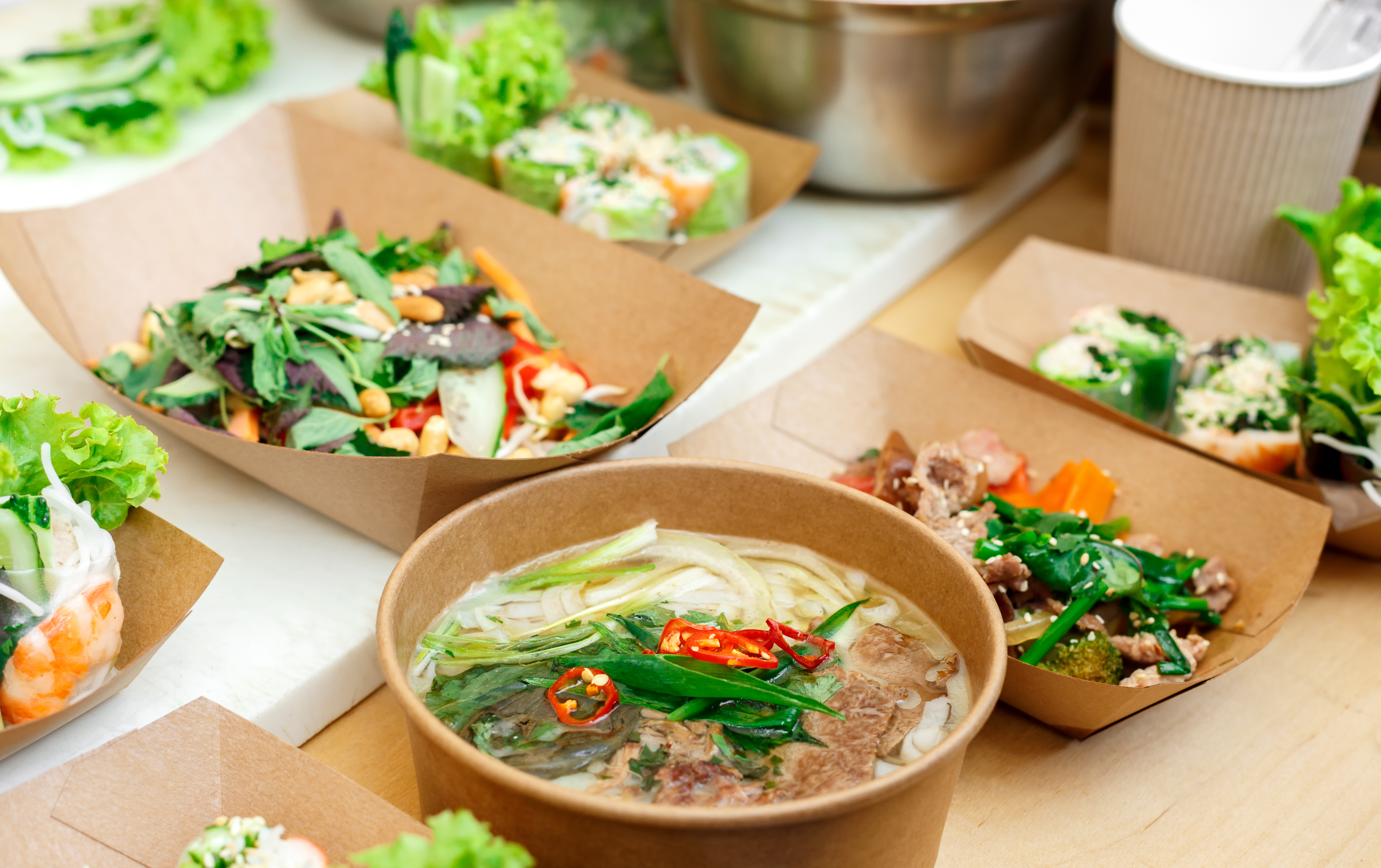 Street vendor's vegetable salads sold outdoors. Snacks closeup, in craft package. Fast food for commercial kitchen.