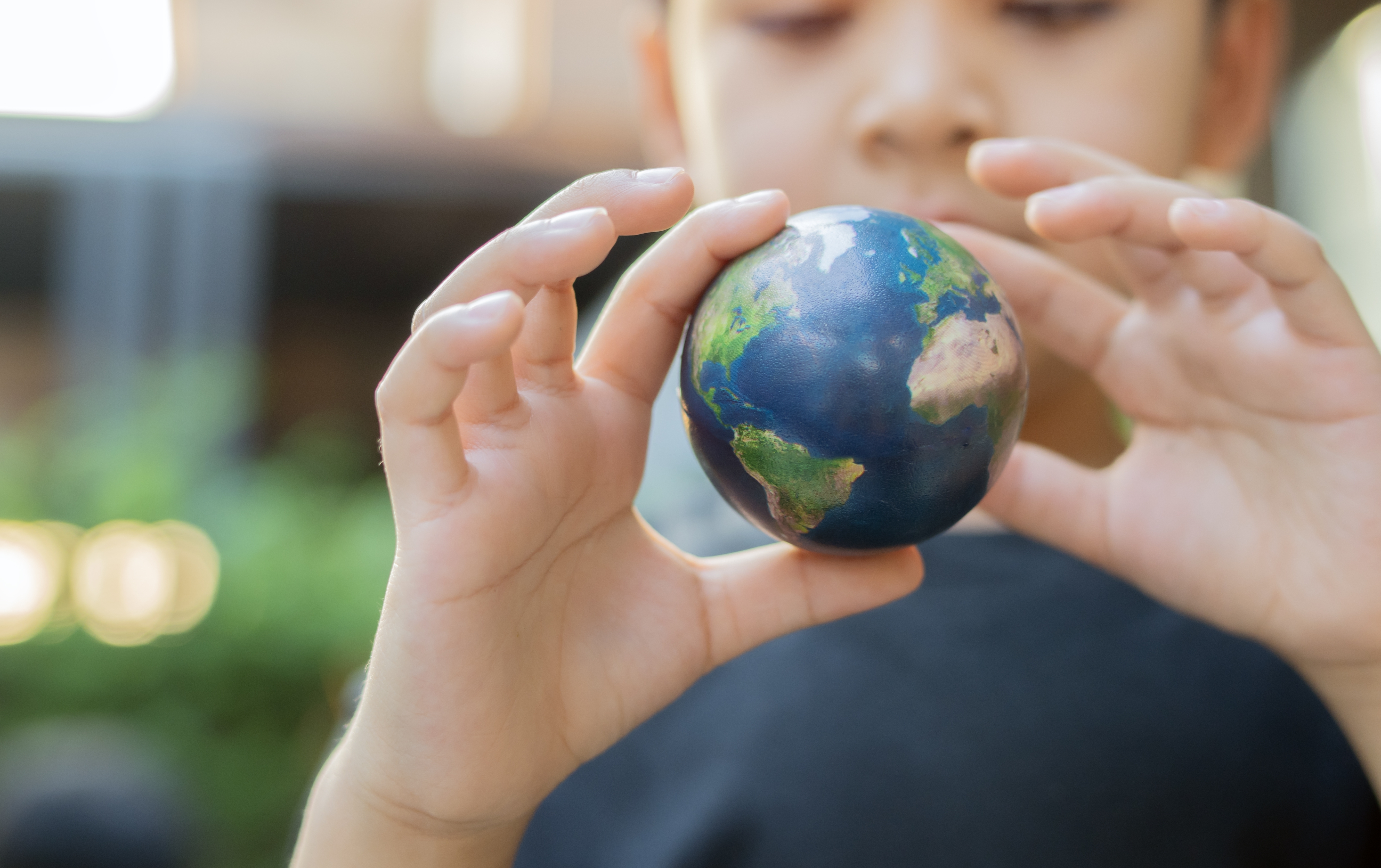 Selective focus of child holding small earth globe outdoor. Concept for future, environment, pollution. Earth Day concept.